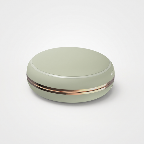 Sage green round rechargeable hand warmer with rose-gold band on a light gray studio background