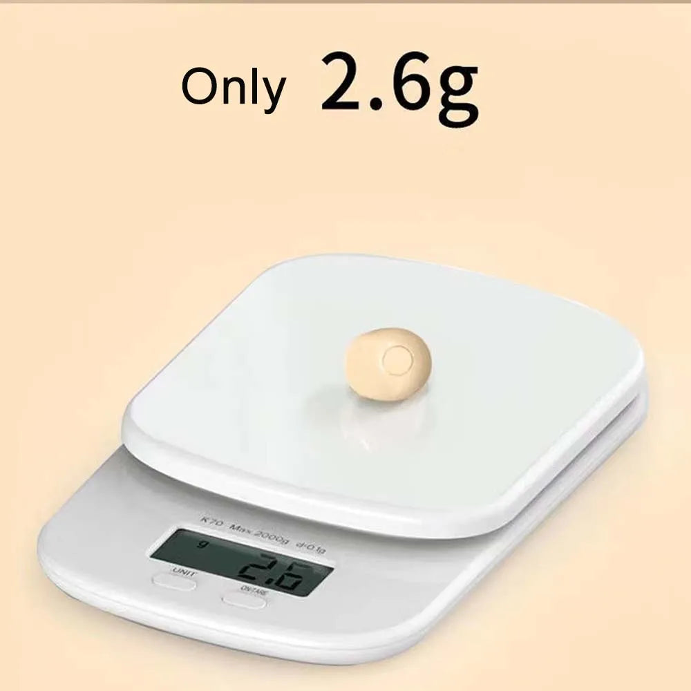 Mini earbud on a kitchen scale showing about 2.6 grams